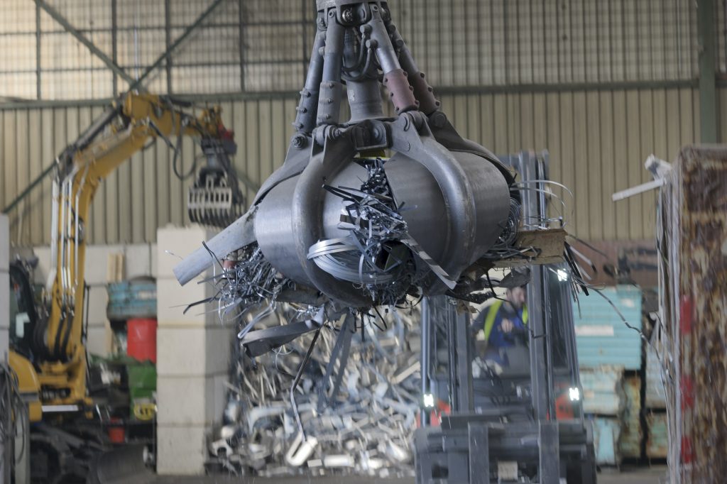 Clamshell grabbing scrap in a scrap metal recycling plant