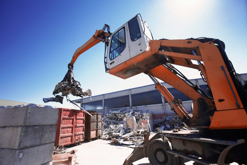 Grapple handler sorting and moving metals in scrap yard